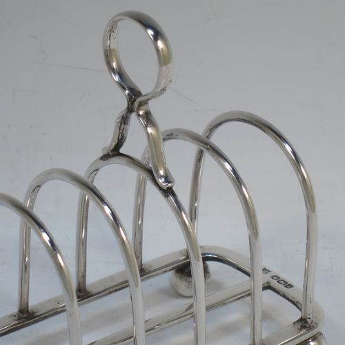 A handsome Sterling Silver five-bar toastrack, having plain rounded wire-work bars, a matching loop handle, all sitting on a rectangular base with a strengthening strut, on four cast ball feet. Made by Thomas Bradbury of Sheffield in 1924. The dimensions of this fine hand-made silver toast-rack are length 11.5 cms (4.5 inches), height 11.5 cms (4.5 inches), width 7 cms (2.75 inches), and it weighs approx. 175g (5.6 troy ounces).