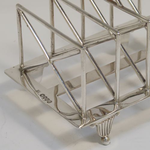 A very unusual Arts and Crafts style Antique Victorian Sterling Silver five-bar toastrack, having square crossed wire-work bars, with a square loop handle, and sitting on a base with a strengthening strut and four fluted and flanged feet. This elegant Arts and Crafts silver toast-rack was made by Edward Hutton of London in 1881. The dimensions of this fine hand-made antique silver toast-rack are length 12.5 cms (5 inches), height 11 cms (4.3 inches), width 9 cms (3.5 inches), and it weighs approx. 259g (8.4 troy ounces).