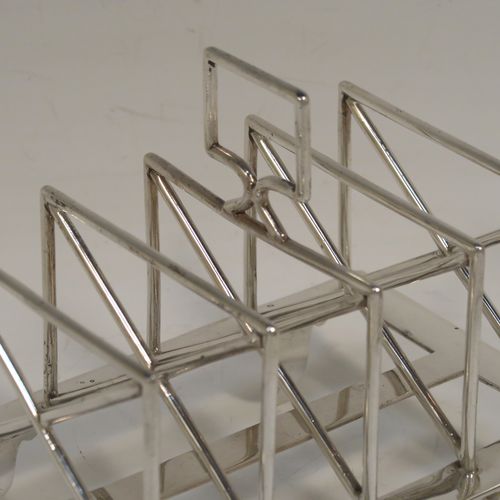 A very unusual Arts and Crafts style Antique Victorian Sterling Silver five-bar toastrack, having square crossed wire-work bars, with a square loop handle, and sitting on a base with a strengthening strut and four fluted and flanged feet. This elegant Arts and Crafts silver toast-rack was made by Edward Hutton of London in 1881. The dimensions of this fine hand-made antique silver toast-rack are length 12.5 cms (5 inches), height 11 cms (4.3 inches), width 9 cms (3.5 inches), and it weighs approx. 259g (8.4 troy ounces).