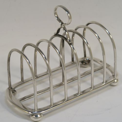 A handsome Antique Sterling Silver seven-bar toastrack, having plain rounded wire-work bars, a matching loop handle, all sitting on a rectangular base with a strengthening strut, on four cast cushion feet. This elegant antique silver toast-rack was made by Goldsmiths and Silversmiths of London in 1916. The dimensions of this fine hand-made antique silver toast-rack are length 16 cms (6.3 inches), height 11.5 cms (4.5 inches), width 8 cms (3 inches), and it weighs approx. 265g (8.5 troy ounces).   