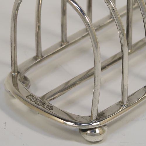 A handsome Antique Sterling Silver seven-bar toastrack, having plain rounded wire-work bars, a matching loop handle, all sitting on a rectangular base with a strengthening strut, on four cast cushion feet. This elegant antique silver toast-rack was made by Goldsmiths and Silversmiths of London in 1916. The dimensions of this fine hand-made antique silver toast-rack are length 16 cms (6.3 inches), height 11.5 cms (4.5 inches), width 8 cms (3 inches), and it weighs approx. 265g (8.5 troy ounces).