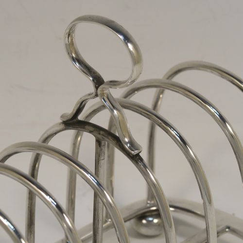 A handsome Antique Sterling Silver seven-bar toastrack, having plain rounded wire-work bars, a matching loop handle, all sitting on a rectangular base with a strengthening strut, on four cast cushion feet. This elegant antique silver toast-rack was made by Goldsmiths and Silversmiths of London in 1916. The dimensions of this fine hand-made antique silver toast-rack are length 16 cms (6.3 inches), height 11.5 cms (4.5 inches), width 8 cms (3 inches), and it weighs approx. 265g (8.5 troy ounces).