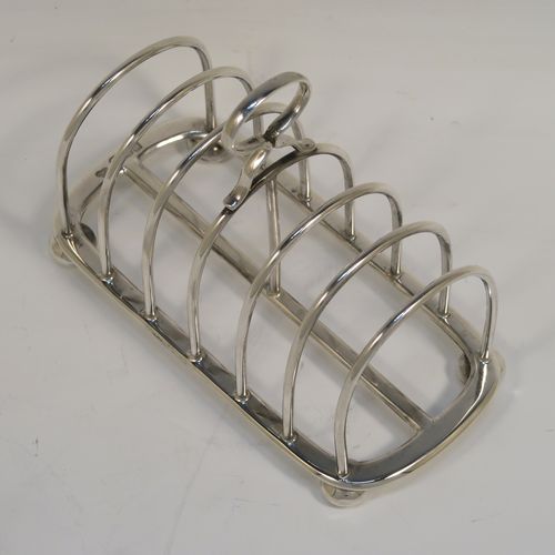 A handsome Antique Sterling Silver seven-bar toastrack, having plain rounded wire-work bars, a matching loop handle, all sitting on a rectangular base with a strengthening strut, on four cast cushion feet. This elegant antique silver toast-rack was made by Goldsmiths and Silversmiths of London in 1916. The dimensions of this fine hand-made antique silver toast-rack are length 16 cms (6.3 inches), height 11.5 cms (4.5 inches), width 8 cms (3 inches), and it weighs approx. 265g (8.5 troy ounces).