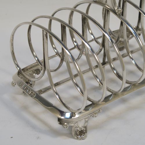 A heavy and elegant Antique Victorian Sterling Silver seven-bar toast-rack, having oval shaped wire-work bars, a cast scroll loop handle, attached to a rectangular base with a strengthening strut, and sitting on four cast shell and scroll feet. This beautiful antique silver toastrack was made by Joseph and John Angell of London in 1841. The dimensions of this fine hand-made antique silver toast-rack are length 16 cms (6.3 inches), height 14 cms (5.5 inches), width 11 cms (4.3 inches), and it weighs approx. 300g (9.7 troy ounces).