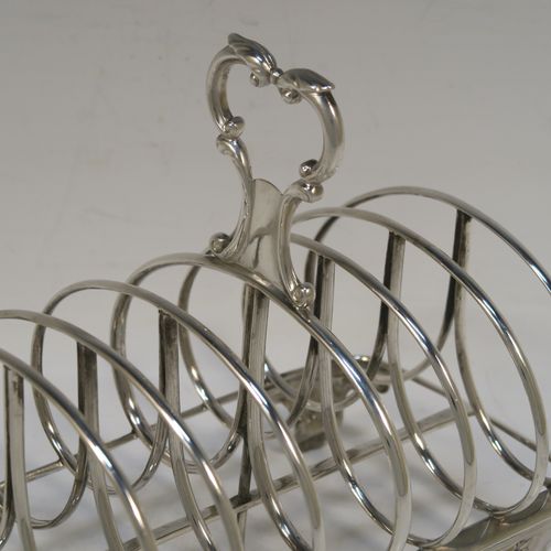 A heavy and elegant Antique Victorian Sterling Silver seven-bar toast-rack, having oval shaped wire-work bars, a cast scroll loop handle, attached to a rectangular base with a strengthening strut, and sitting on four cast shell and scroll feet. This beautiful antique silver toastrack was made by Joseph and John Angell of London in 1841. The dimensions of this fine hand-made antique silver toast-rack are length 16 cms (6.3 inches), height 14 cms (5.5 inches), width 11 cms (4.3 inches), and it weighs approx. 300g (9.7 troy ounces).