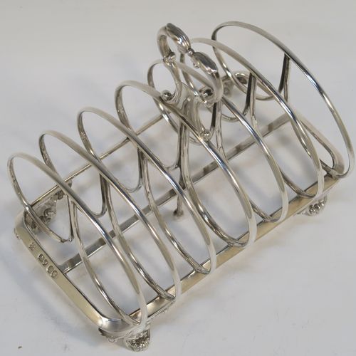 A heavy and elegant Antique Victorian Sterling Silver seven-bar toast-rack, having oval shaped wire-work bars, a cast scroll loop handle, attached to a rectangular base with a strengthening strut, and sitting on four cast shell and scroll feet. This beautiful antique silver toastrack was made by Joseph and John Angell of London in 1841. The dimensions of this fine hand-made antique silver toast-rack are length 16 cms (6.3 inches), height 14 cms (5.5 inches), width 11 cms (4.3 inches), and it weighs approx. 300g (9.7 troy ounces).