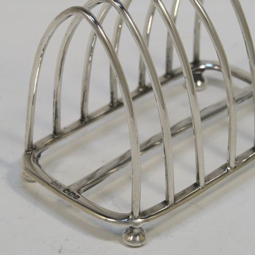 A very handsome Antique Victorian Sterling Silver seven-bar toastrack, having plain arched cross-section wire-work bars, an unusual loop handle, all sitting on a rectangular base with a strengthening strut, on four cast cushion feet. This elegant antique silver toast-rack was made by Walker and Hall of Sheffield in 1894. The dimensions of this fine hand-made antique silver toast-rack are length 12 cms (4.75 inches), height 12 cms (4.75 inches), width 7 cms (2.75 inches), and it weighs approx. 196g (6.3 troy ounces).