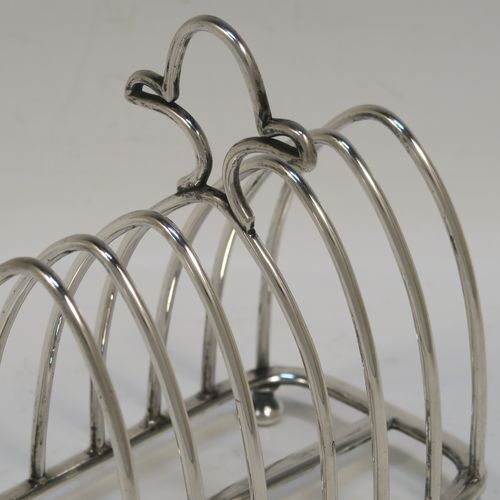 A very handsome Antique Victorian Sterling Silver seven-bar toastrack, having plain arched cross-section wire-work bars, an unusual loop handle, all sitting on a rectangular base with a strengthening strut, on four cast cushion feet. This elegant antique silver toast-rack was made by Walker and Hall of Sheffield in 1894. The dimensions of this fine hand-made antique silver toast-rack are length 12 cms (4.75 inches), height 12 cms (4.75 inches), width 7 cms (2.75 inches), and it weighs approx. 196g (6.3 troy ounces).