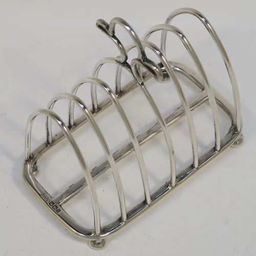 A very handsome Antique Victorian Sterling Silver seven-bar toastrack, having plain arched cross-section wire-work bars, an unusual loop handle, all sitting on a rectangular base with a strengthening strut, on four cast cushion feet. This elegant antique silver toast-rack was made by Walker and Hall of Sheffield in 1894. The dimensions of this fine hand-made antique silver toast-rack are length 12 cms (4.75 inches), height 12 cms (4.75 inches), width 7 cms (2.75 inches), and it weighs approx. 196g (6.3 troy ounces).