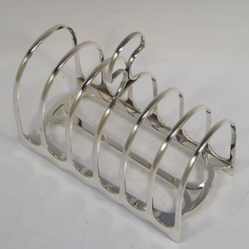 A handsome and heavy Antique Victorian Sterling Silver seven-bar toastrack, having plain rounded wire-work bars, a matching loop handle, all sitting on a rectangular base with a strengthening strut. This elegant antique silver toast-rack was made by William Hutton of London in 1898. The dimensions of this fine hand-made antique silver toast-rack are length 15 cms (6 inches), height 15 cms (6 inches), width 8 cms (3 inches), and it weighs approx. 305g (9.8 troy ounces).