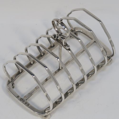 A very elegant Antique Victorian Sterling Silver seven-bar toastrack, having plain shaped cross-section wire-work bars, a matching loop handle, and all sitting on a rectangular base with four cast octagonal panelled feet. This handsome antique silver toast-rack was made by Martin and Hall of London in 1888. The dimensions of this fine hand-made antique silver toast-rack are length 13.5 cms (5.25 inches), height 11 cms (4.25 inches), width 8.5 cms (3.3 inches), and it weighs approx. 203g (6.5 troy ounces).
