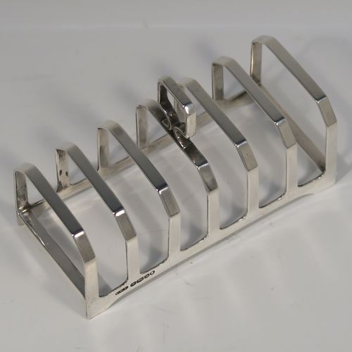 An elegant Art Deco Sterling Silver seven-bar toast-rack, in a very angular style design, with a square-shaped handle, all attached to a rectangular base, and sitting on four flange legs. This handsome silver toastrack was made by C. W. Fletcher of Sheffield in 1935. The dimensions of this fine hand-made Art Deco silver toast-rack are length 11.5 cms (4.5 inches), height 8 cms (3 inches), width 5 cms (2 inches), and it weighs approx. 91g (3 troy ounces).