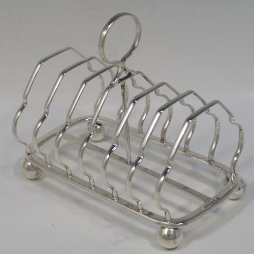 A very elegant Antique Victorian Sterling Silver seven-bar toastrack, having plain shaped cross-section wire-work bars, a round loop handle, and all sitting on a rectangular base with a strengthening strut and with four cast ball feet. This handsome antique silver toast-rack was made by William Morton and Sons of Sheffield in 1899. The dimensions of this fine hand-made antique silver toast-rack are length 15 cms (6 inches), height 13 cms (5 inches), width 9 cms (3.5 inches), and it weighs approx. 234g (7.5 troy ounces).   