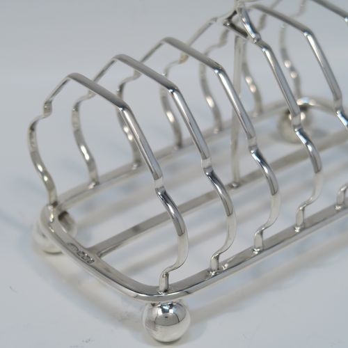 A very elegant Antique Victorian Sterling Silver seven-bar toastrack, having plain shaped cross-section wire-work bars, a round loop handle, and all sitting on a rectangular base with a strengthening strut and with four cast ball feet. This handsome antique silver toast-rack was made by William Morton and Sons of Sheffield in 1899. The dimensions of this fine hand-made antique silver toast-rack are length 15 cms (6 inches), height 13 cms (5 inches), width 9 cms (3.5 inches), and it weighs approx. 234g (7.5 troy ounces).