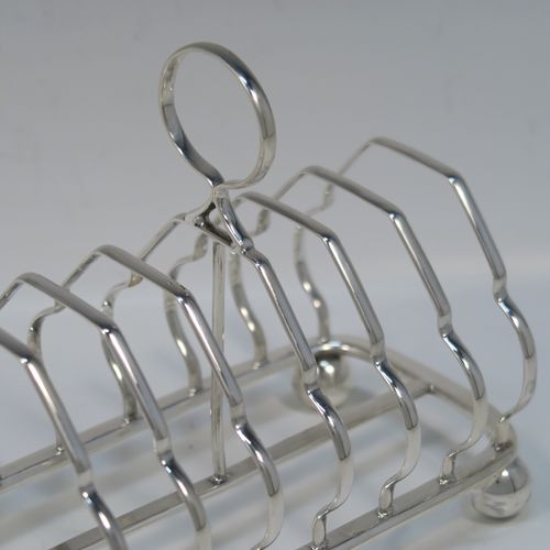 A very elegant Antique Victorian Sterling Silver seven-bar toastrack, having plain shaped cross-section wire-work bars, a round loop handle, and all sitting on a rectangular base with a strengthening strut and with four cast ball feet. This handsome antique silver toast-rack was made by William Morton and Sons of Sheffield in 1899. The dimensions of this fine hand-made antique silver toast-rack are length 15 cms (6 inches), height 13 cms (5 inches), width 9 cms (3.5 inches), and it weighs approx. 234g (7.5 troy ounces).