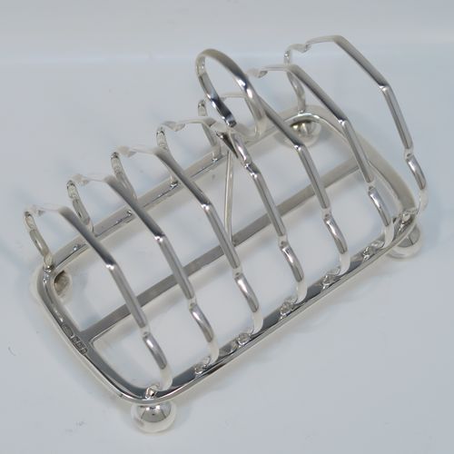 A very elegant Antique Victorian Sterling Silver seven-bar toastrack, having plain shaped cross-section wire-work bars, a round loop handle, and all sitting on a rectangular base with a strengthening strut and with four cast ball feet. This handsome antique silver toast-rack was made by William Morton and Sons of Sheffield in 1899. The dimensions of this fine hand-made antique silver toast-rack are length 15 cms (6 inches), height 13 cms (5 inches), width 9 cms (3.5 inches), and it weighs approx. 234g (7.5 troy ounces).