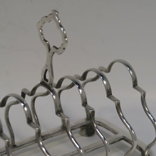 A pretty Antique Sterling Silver seven-bar toastrack, having plain shaped and lobed cross-section wire-work bars, a matching loop handle, and all sitting on a rectangular base with a strengthening strut and four ball feet. This handsome antique silver toast-rack was made by William Hutton of Sheffield in 1912. The dimensions of this fine hand-made antique silver toast-rack are length 16.5 cms (6.5 inches), height 12.5 cms (5 inches), width 8.5 cms (3.3 inches), and it weighs approx. 265g (8.5 troy ounces).