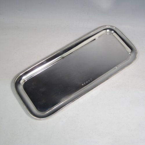 Sterling silver sandwich tray, having a rectangular body with rounded corners, a very plain ground, a raised border with an applied gadroon edge, and sitting on a flat base. Made by the Barker Brothers of Birmingham in 1921. The dimensions of this fine hand-made silver sandwich tray are length 39.5 cms (15.5 inches), width 17 cms (6.75 inches), and it weighs approx. 640g (20.6 troy ounces).