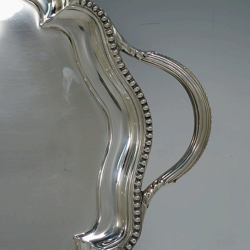 A very pretty Antique Victorian Sterling Silver tray, having a shaped oval body with a plain ground, an applied bead-edged border, and two cast reeded handles, all sitting on a flat base. This beautiful silver tray was made by John Brashier of London in 1879. The dimensions of this fine hand-made antique silver tray are length 60 cms (23.5 inches), width 39.5 cms (15.5 inches), and it weighs approx. 2,110g (68 troy ounces).