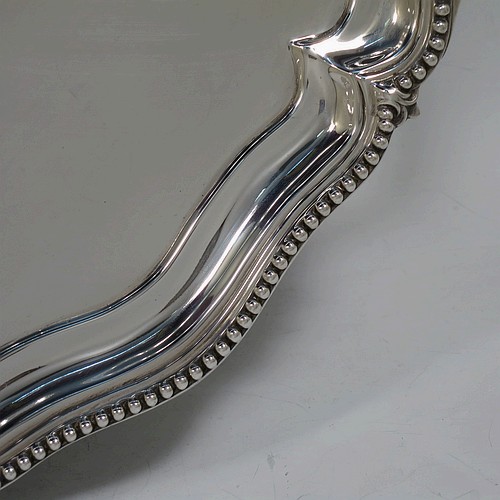 A very pretty Antique Victorian Sterling Silver tray, having a shaped oval body with a plain ground, an applied bead-edged border, and two cast reeded handles, all sitting on a flat base. This beautiful silver tray was made by John Brashier of London in 1879. The dimensions of this fine hand-made antique silver tray are length 60 cms (23.5 inches), width 39.5 cms (15.5 inches), and it weighs approx. 2,110g (68 troy ounces).