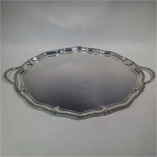 A very pretty Antique Victorian Sterling Silver tray, having a shaped oval body with a plain ground, an applied bead-edged border, and two cast reeded handles, all sitting on a flat base. This beautiful silver tray was made by John Brashier of London in 1879. The dimensions of this fine hand-made antique silver tray are length 60 cms (23.5 inches), width 39.5 cms (15.5 inches), and it weighs approx. 2,110g (68 troy ounces).