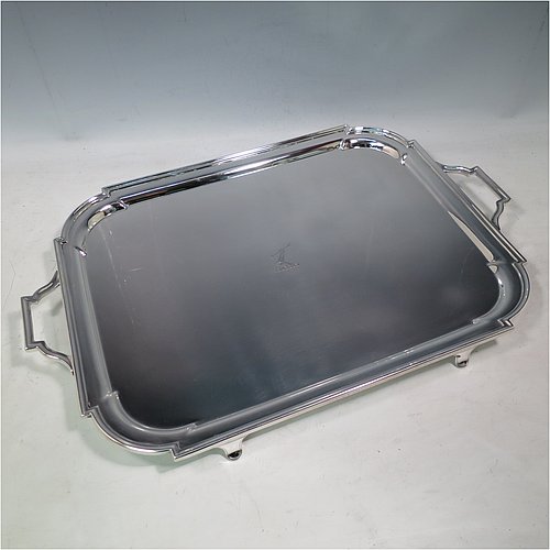 An Antique Edwardian heavy Sterling Silver Georgian style tea tray, having a rectangular body with rounded cut corners, a very plain ground with a centrally engraved crest, an applied reeded border, two cast scroll side-handles, and sitting on four cast flanged feet. Made by Thomas Bradbury of London in 1905. The dimensions of this fine hand-made antique silver tray are length (inc. handles) 53 cms (20.75 inches), width 35 cms (13.75 inches), and it weighs approx. 2,325g (75 troy ounces). Please note that this item is crested.