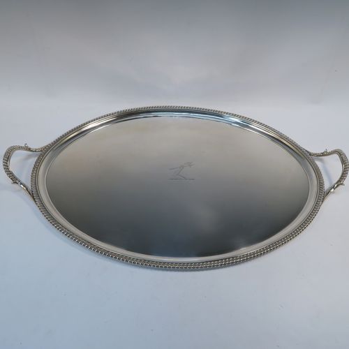 A very elegant Antique Georgian Sterling Silver tray, having an oval body with a plain central ground which is engraved with a part crest, with an applied gadroon border, and two cast gadroon and anthemion leaf side-handles, all sitting on a flat base. This beautiful antique silver tray was made by Crouch and Hannam of London in 1796. The dimensions of this fine hand-made antique silver tray are length (inc. handles) 62 cms (24.5 inches), width 40.5 cms (16 inches), and it weighs approx. 2,460g (79 troy ounces).   