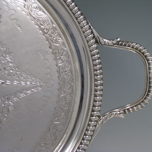 Antique Georgian sterling silver oval two-handled tea tray with beautifully hand-engraved floral and swag decoration, and cast gadroon border. This handsome sterling silver tray was made by William Bennett of London in 1805. The dimensions of this fine hand-made silver tray are length inc. handles 53 cms (21 inches), width 33 cms (13 inches), and it weighs approx. 1,550g (50 troy ounces). Please note that this item is crested in the central cartouche.