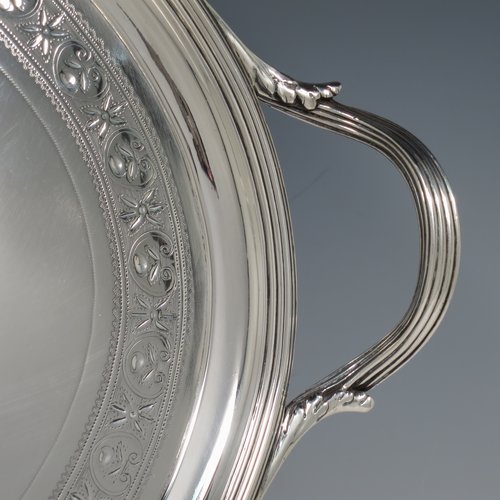 An Antique Georgian Sterling silver oval two-handled tea tray, with a beautifully hand-engraved band of floral decoration, an applied reeded border with matching cast handles, and sitting on a flat base. This handsome Georgian sterling silver tray was made by Elizabeth Jones of London in 1794. The dimensions of this fine hand-made silver tray are length inc. handles 52 cms (20.5 inches), width 34 cms (13.5 inches), and it weighs approx. 1,593g (51 troy ounces).