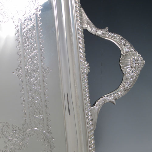 Antique Edwardian sterling silver tea tray, having a rectangular body, with applied cast gadroon and shell border, two cast handles, and a hand-engraved ground with floral decoration, all sitting on a flat base. Made by Mappin and Webb of Sheffield in 1905. The dimensions of this fine hand-made silver tea tray are length (inc. handles) 70 cms (27.5 inches), width 41 cms (16 inches), and it weighs approx. 3,410g (110 troy ounces).