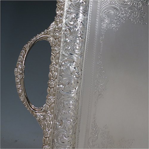 A very pretty Antique Victorian Silver Plated tray, having a rectangular body, a beautiful hand-engraved ground with floral decoration surrounding a central vacant cartouche, a hand-chased border with floral and scroll decoration, with two cast gadroon side-handles, and sitting on a flat base. This beautiful silver-plated tray was made by the Mappin Brothers of Sheffield in their top-quality Queens Plate. The dimensions of this fine hand-made silver plated tea tray are length (inc. handles) 58 cms (22.75 inches), width 38 cms (15 inches).