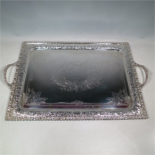A very pretty Antique Victorian Silver Plated tray, having a rectangular body, a beautiful hand-engraved ground with floral decoration surrounding a central vacant cartouche, a hand-chased border with floral and scroll decoration, with two cast gadroon side-handles, and sitting on a flat base. This beautiful silver-plated tray was made by the Mappin Brothers of Sheffield in their top-quality Queens Plate. The dimensions of this fine hand-made silver plated tea tray are length (inc. handles) 58 cms (22.75 inches), width 38 cms (15 inches).