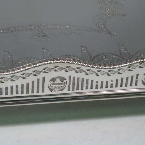 Antique Victorian sterling silver gallery tray, having an octagonal body, with an engraved ground with neoclassical style hand-engraving, a hand-pierced gallery border with shaped gadroon edge and cut-out handles, all sitting on four cast foliate feet. This very handsome sterling silver tray was made by Page, Keen, and Page of London in 1901. The dimensions of this fine hand-made silver gallery tray are length 53 cms (21 inches), width 35 cms (13.75 inches), height 8.5 cms (3.3 inches), and it weighs approx. 3,161g (102 troy ounces).