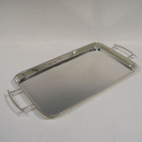 A very handsome and stylish Art Deco Sterling silver tray, having a very plain ground, a raised gallery border with rounded corners, two side-handles, and sitting on a flat base. This elegant Art Deco silver tray was made by Walker and Hall of Sheffield in 1932. The dimensions of this fine hand-made silver tray are length (inc. handles) 38 cms (15 inches), width 18.5 cms (7.25 inches), and it weighs approx. 620g (20 troy ounces).   