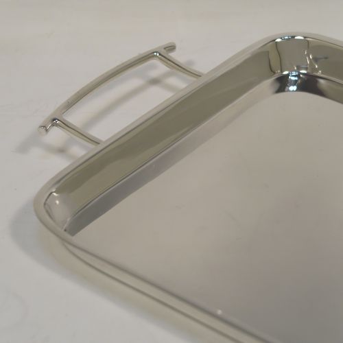 A very handsome and stylish Art Deco Sterling silver tray, having a very plain ground, a raised gallery border with rounded corners, two side-handles, and sitting on a flat base. This elegant Art Deco silver tray was made by Walker and Hall of Sheffield in 1932. The dimensions of this fine hand-made silver tray are length (inc. handles) 38 cms (15 inches), width 18.5 cms (7.25 inches), and it weighs approx. 620g (20 troy ounces).