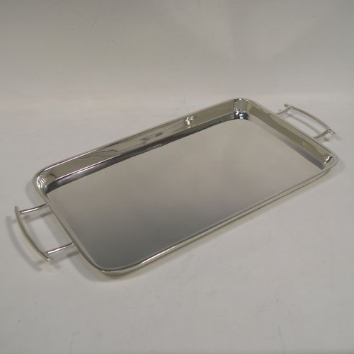 A very handsome and stylish Art Deco Sterling silver tray, having a very plain ground, a raised gallery border with rounded corners, two side-handles, and sitting on a flat base. This elegant Art Deco silver tray was made by Walker and Hall of Sheffield in 1932. The dimensions of this fine hand-made silver tray are length (inc. handles) 38 cms (15 inches), width 18.5 cms (7.25 inches), and it weighs approx. 620g (20 troy ounces).