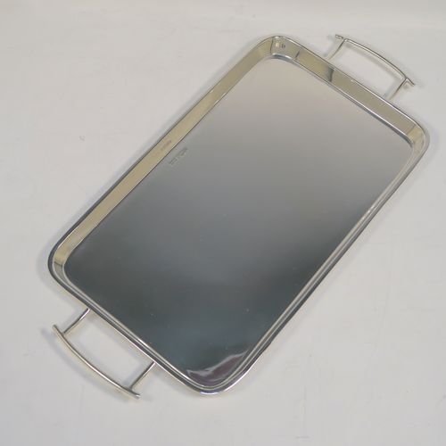 A very handsome and stylish Art Deco Sterling silver tray, having a very plain ground, a raised gallery border with rounded corners, two side-handles, and sitting on a flat base. This elegant Art Deco silver tray was made by Walker and Hall of Sheffield in 1932. The dimensions of this fine hand-made silver tray are length (inc. handles) 38 cms (15 inches), width 18.5 cms (7.25 inches), and it weighs approx. 620g (20 troy ounces).