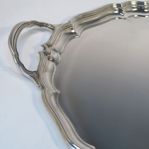 A very handsome Sterling Silver oval two-handled tea tray, having a plain ground, with an applied Chippendale border, two cast side handles, and all sitting on a flat base. This elegant silver tray was made by Harrison Brothers and Howson of Sheffield in 1928. The dimensions of this fine hand-made sterling silver tray are length (inc. handles) 70 cms (27.5 inches), width 43 cms (17 inches), and it weighs approx. 3,100g (100 troy ounces).