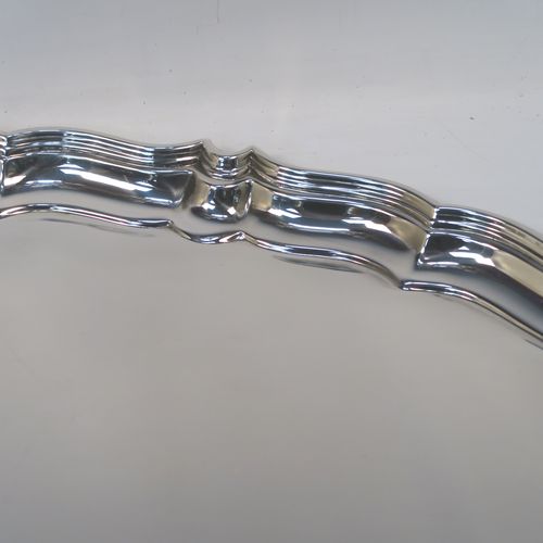 A very handsome Sterling Silver oval two-handled tea tray, having a plain ground, with an applied Chippendale border, two cast side handles, and all sitting on a flat base. This elegant silver tray was made by Harrison Brothers and Howson of Sheffield in 1928. The dimensions of this fine hand-made sterling silver tray are length (inc. handles) 70 cms (27.5 inches), width 43 cms (17 inches), and it weighs approx. 3,100g (100 troy ounces).