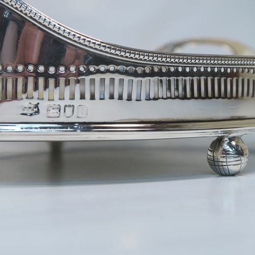 A very handsome Antique Victorian Sterling Silver galleried drinks tray, having an oval body with a hand-pierced gallery, with two oval cut-out side-handles, an applied bead-edged top border, a plain oval ground, and sitting on four cast ball feet. This elegant antique silver drinks tray was made by John Newton Mappin of London in 1896. The dimensions of this fine hand-made silver gallery tray are length 39 cms (15.3 inches), width 26.5 cms (10.5 inches), and it weighs approx. 1,115g (36 troy ounces).
