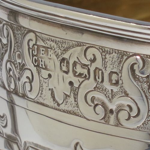 A very beautiful Antique Victorian Sterling Silver trophy cup, having a round body with tapering sides all hand-chased with floral and scroll decoration surrounding vacant cartouches either side, two cast scroll handles with figural thumb-pieces, a gold-gilt interior, and all sitting on a pedestal foot. Made by John Edward Bingham and Charles Henry Bingham of Sheffield in 1876. The dimensions of this fine hand-made antique silver trophy cup are height 24 cms (9.5 inches), spread across arms 22 cms (8.75 inches), and it weighs approx. 620g (20 troy ounces).