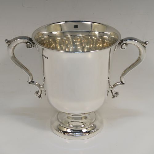 A very handsome Antique Sterling Silver trophy cup in a George III style, having a plain round bellied body, two scroll side-handles, and all sitting on a round pedestal foot. This elegant antique sterling silver trophy cup was made by Martin Hall and Co. Ltd., of Sheffield in 1922. The dimensions of this fine hand-made silver trophy cup are height 16 cms (6.3 inches), spread across arms 21.5 cms (8.5 inches), and it weighs approx. 390g (12.6 troy ounces).   