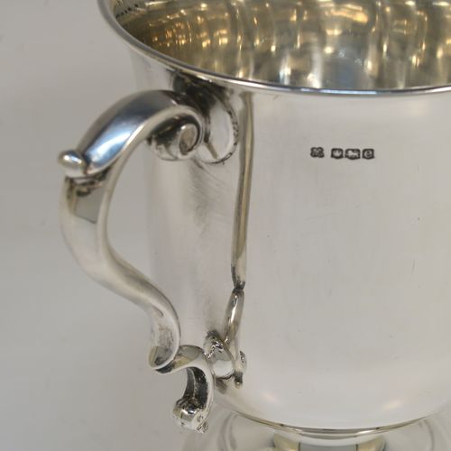 A very handsome Antique Sterling Silver trophy cup in a George III style, having a plain round bellied body, two scroll side-handles, and all sitting on a round pedestal foot. This elegant antique sterling silver trophy cup was made by Martin Hall and Co. Ltd., of Sheffield in 1922. The dimensions of this fine hand-made silver trophy cup are height 16 cms (6.3 inches), spread across arms 21.5 cms (8.5 inches), and it weighs approx. 390g (12.6 troy ounces).