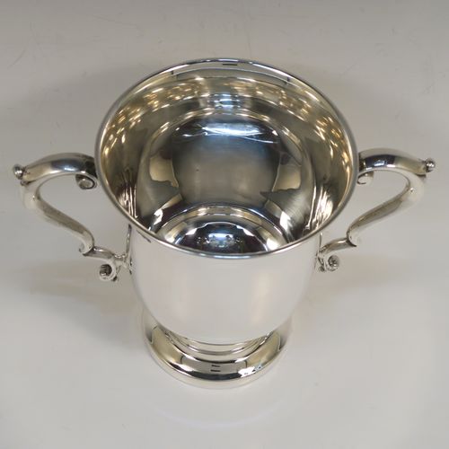 A very handsome Antique Sterling Silver trophy cup in a George III style, having a plain round bellied body, two scroll side-handles, and all sitting on a round pedestal foot. This elegant antique sterling silver trophy cup was made by Martin Hall and Co. Ltd., of Sheffield in 1922. The dimensions of this fine hand-made silver trophy cup are height 16 cms (6.3 inches), spread across arms 21.5 cms (8.5 inches), and it weighs approx. 390g (12.6 troy ounces).