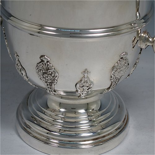 A Sterling Silver trophy cup and cover, in a George II style, having a round body with applied floral strap-work decoration, two scroll side-handles with anthemion leaf thumb-pieces, a central applied girdle band, a pull-off lid with matching applied strap-work and a cast round finial, and all sitting on a stepped pedestal foot. Made by George Bryan & Co., of Birmingham in 1936. The dimensions of this fine hand-made silver trophy cup and cover are height 30 cms (11.75 inches), spread across arms 26.5 cms (10.5 inches), and it weighs approx. 1,132g (36.5 troy ounces).