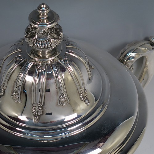 A very handsome Antique Edwardian Sterling Silver trophy cup and cover, in a George II style, having a round body with applied floral strap-work decoration, two scroll side-handles with anthemion leaf thumb-pieces, a central applied girdle band, a pull-off lid with matching applied strap-work and a cast round floral finial, and all sitting on a stepped pedestal foot. Made by Walker and Hall of Sheffield in 1909. The dimensions of this fine hand-made antique silver trophy cup and cover are height 37 cms (14.5 inches), spread across arms 33 cms (13 inches), and it weighs approx. 1,570g (51 troy ounces).