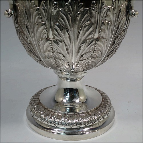 A very large, heavy, and handsome Antique Edwardian Sterling Silver three-handled trophy cup, having a round body with tapering sides and hand-chased half anthemion leaf decoration, with a gold-gilt interior, three cast flying scroll handles with leopard face terminals, and all sitting on a pedestal foot. Made by Goldsmiths and Silversmiths of London in 1905. The dimensions of this fine hand-made large antique silver trophy cup are height 43 cms (17 inches), spread across arms 38 cms (15 inches), and it weighs approx. 3,225g (104 troy ounces).