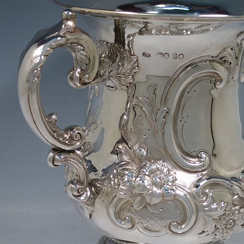 An impressive Antique Victorian Sterling Silver trophy cup, in a Campana style, having a bellied body with cartouches on both sides, with hand-chased floral and scroll decoration, with two floral scroll handles, and sitting on a pedestal foot. This beautiful antique silver trophy cup was made by Charles Boyton of London in 1861. The dimensions of this fine hand-made antique silver trophy cup are height 26 cms (10.25 inches), spread across handles 30 cms (11.75 inches), and it weighs approx. 1,291g (42 troy ounces). Please note that this item is crested on one side.