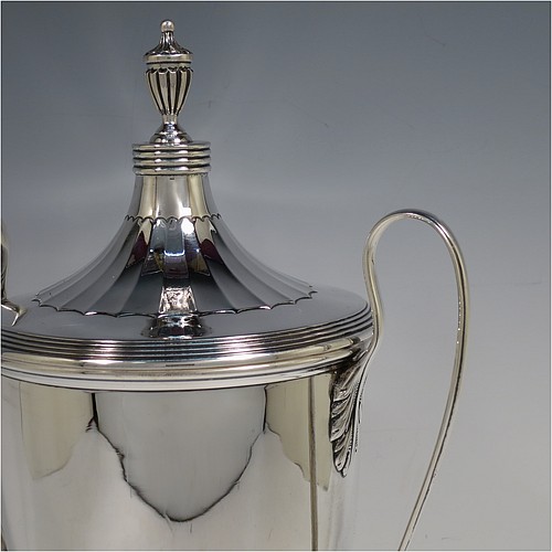 A very handsome Sterling Silver trophy cup and cover in a George III neoclassical style, having a round body with tapering sides and half-fluted decoration, with hand-chased reeded borders, two looped side-handles, an original cover with matching decoration and cast urn finial, and all sitting on a pedestal foot. Made by Robert Pringle of London in 1923. The dimensions of this fine hand-made silver trophy cup and cover are height 33 cms (13 inches), spread across arms 21 cms (8.25 inches), and it weighs approx. 879g (28 troy ounces).