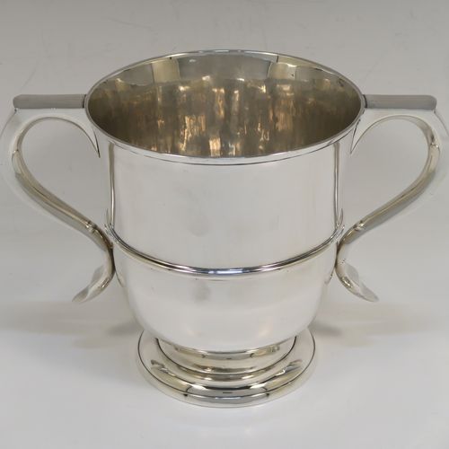 A very elegant Antique Edwardian Sterling Silver trophy loving cup, having a plain round body with a  central reeded band, two flat-topped scroll side-handles, and sitting on a round pedestal foot. This handsome antique silver loving cup trophy was made by Robert Dicker of London in 1904. The dimensions of this fine antique silver loving cup are height 14.5 cms (5.75 inches), spread across handles 21.5 cms (8.5 inches), and it weighs approx. 604g (19.5 troy ounces).   